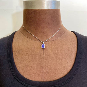 emerald cut tanzanite gemstone set in white gold pendant with diamond accents